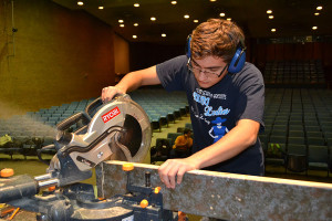 Focusing on the cut, junior Austin Zessin slices a piece of wood using the miter saw. 