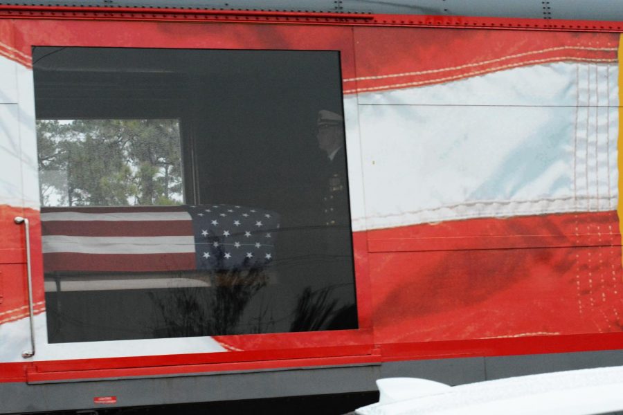A solider stands guard by the flag draped casket of Former President George HW Bush as the train passes by thousands of community members on its way to College Station.