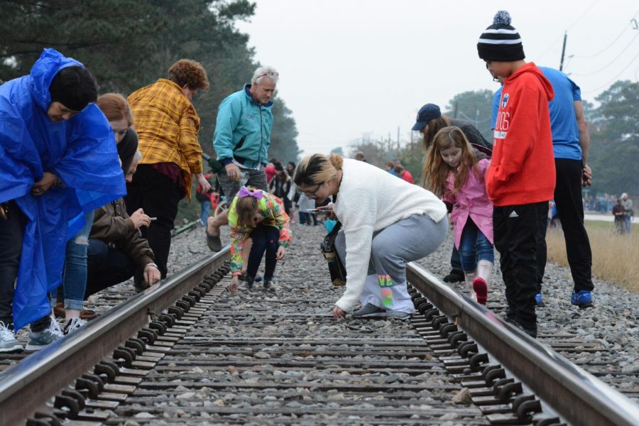 Community members pick up coins they laid on the track before the train came through. The coins were flattened by the train and served as mementos.