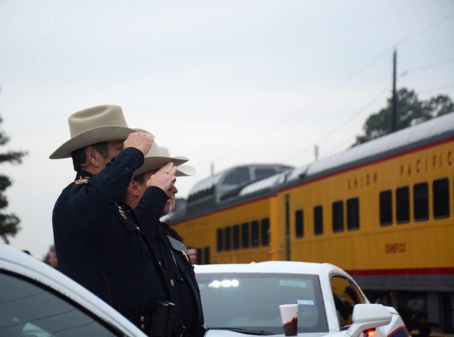 Members of the Klein ISD Police salute as the train carrying the casket of Former President George HW Bush passes by Klein Oak High School on Dec. 6