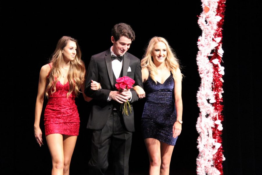 Senior Jack Smith walks with his escorts as he holds flowers.