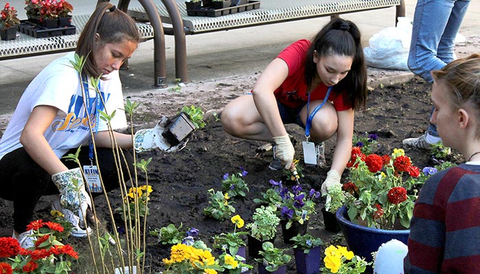 Klein High students plant flowers in a garden near the front of the school.