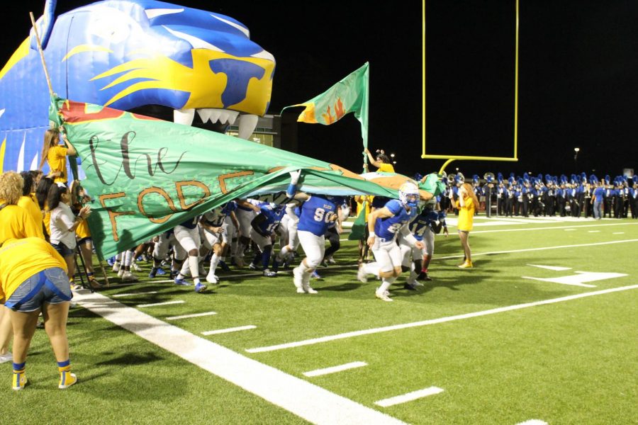 Football players run out onto the field at the homecoming game against Klein Forest.