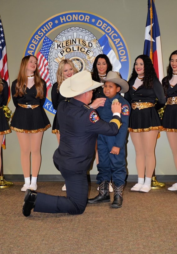 Police Chief David Kimberly pins an official Klein ISD police badge on 10-year-old DJ Daniel during his swearing in ceremony as an honorary KISD police officer.